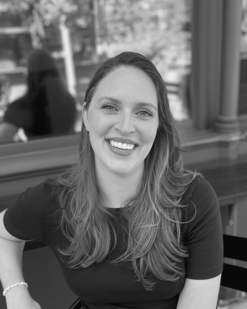 Jill Pierce, photographed outdoors, seated and smiling.